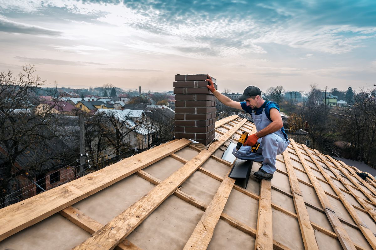  A man using a saw to work on a roof, focused on his task while wearing safety gear.